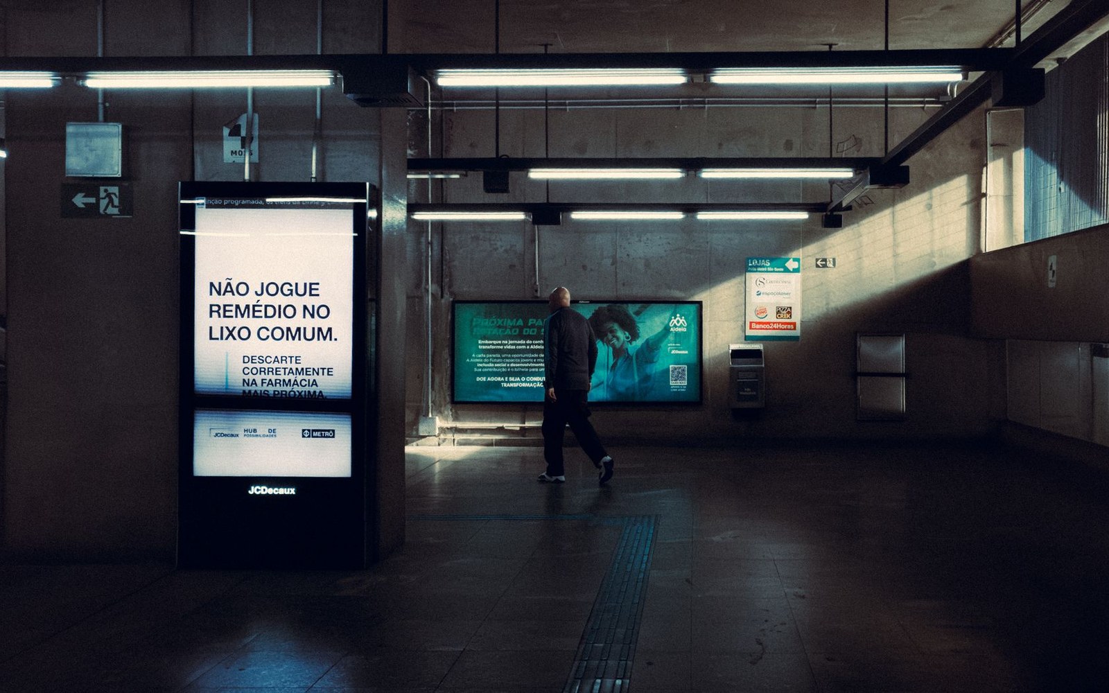 Arena concourse with a large fight-card poster on the wall, adult figures passing in foreground
