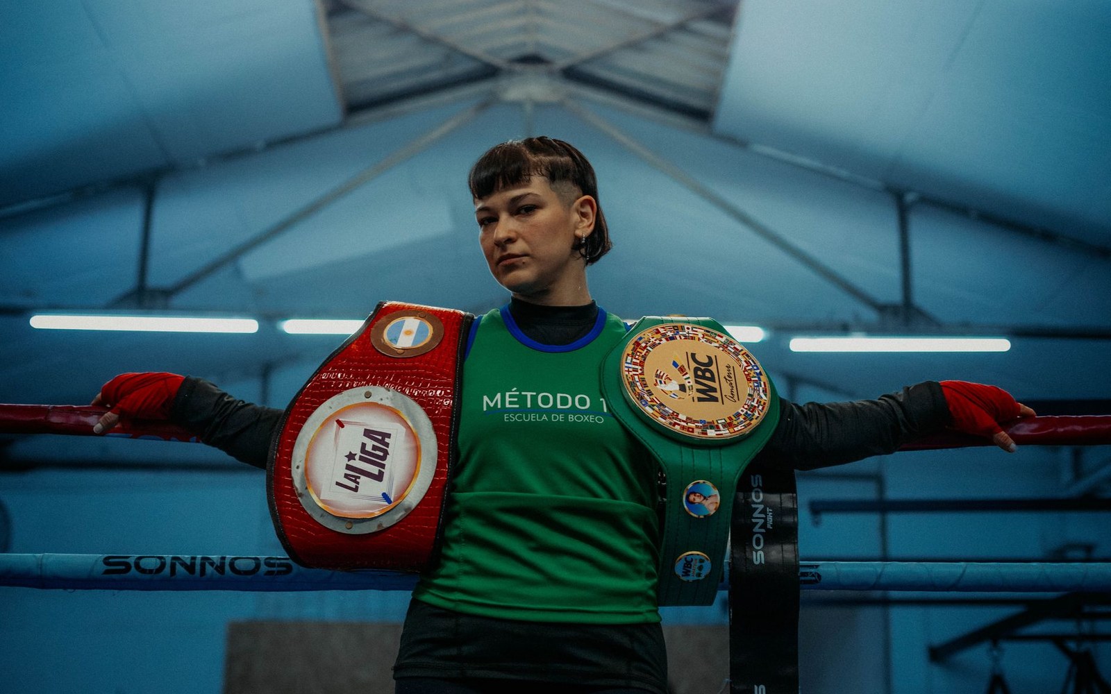 A boxer drapes a WBC championship belt and another title belt over the ring ropes