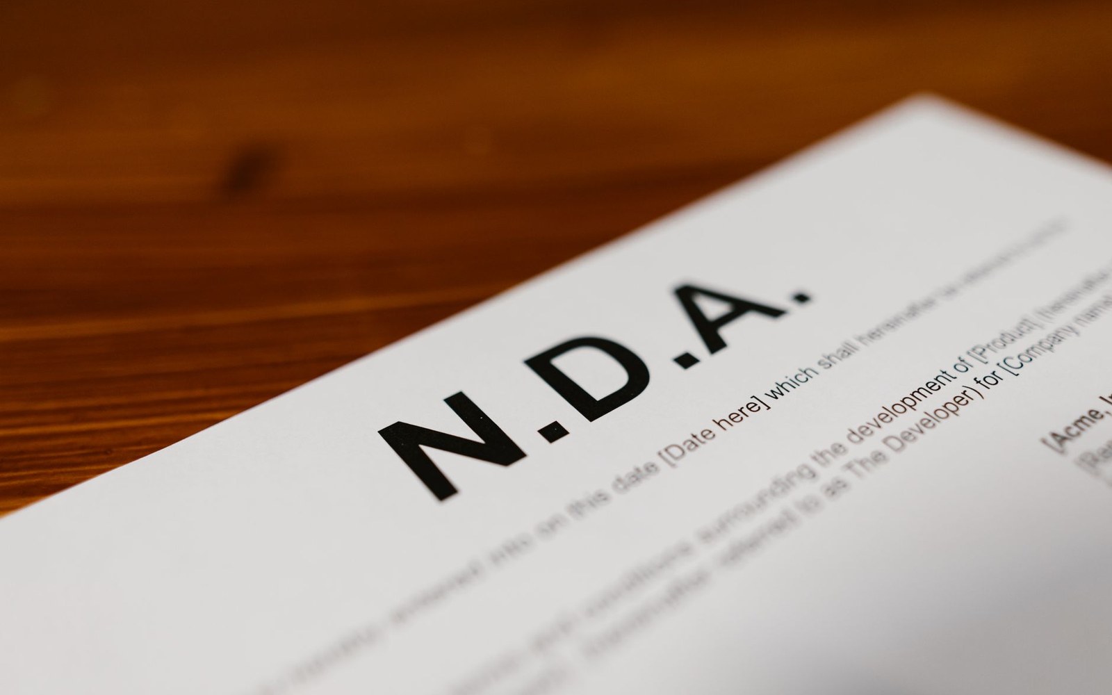 A printed non-disclosure agreement document lies on a wooden table