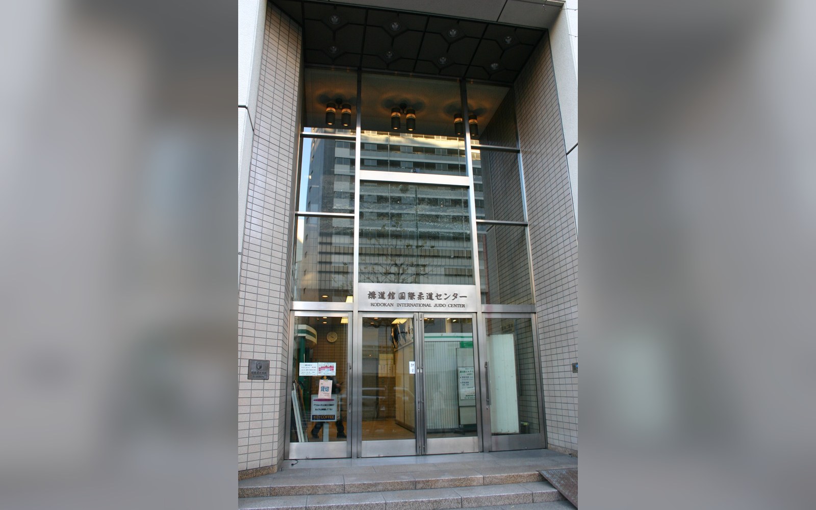 Glass-fronted entrance of the Kodokan International Judo Center with tiled facade and signage